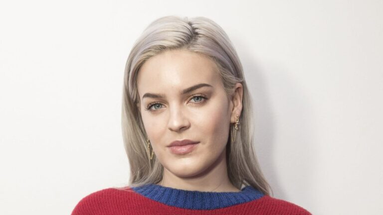 Anne-Marie performing live on stage, wearing a sparkling outfit, with microphone in hand, 2026 tour