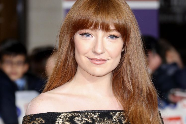 Nicola Roberts performing on stage, smiling confidently in a glittering outfit, representing her Girls Aloud and solo career achievements
