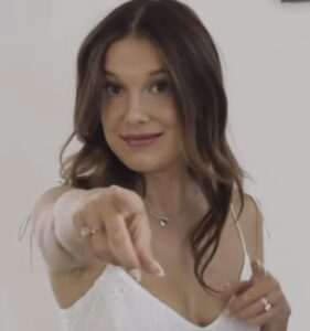 Millie Bobby Brown posing on the red carpet, smiling in a stylish outfit, star of Stranger Things, Enola Holmes, and Netflix’s Damsel