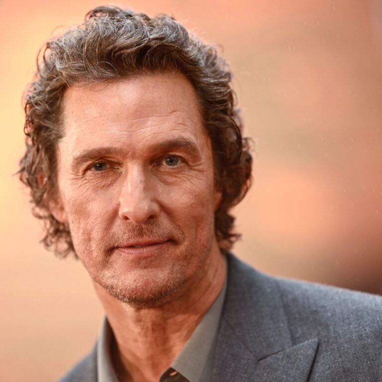“Matthew McConaughey smiling in a suit on the red carpet, Hollywood actor, author, and cultural icon.”