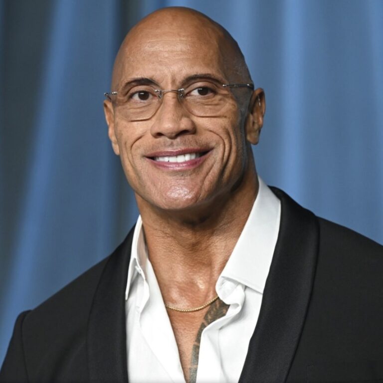 “Dwayne Johnson smiling on red carpet, wearing a suit, showcasing his Hollywood superstar charisma”