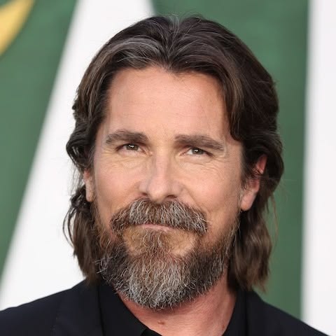 “Christian Bale posing on a red carpet in black suit, representing his iconic Hollywood career and transformative acting roles”